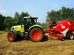 Trator verde equipado com enfardadora trabalhando em um campo agrícola, com árvores ao fundo.