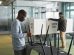 Homens preparam cabines de votação em um ambiente interno para o dia da eleição.