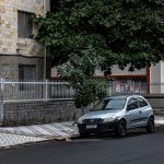 Rua urbana tranquila com prédios residenciais e um carro estacionado.