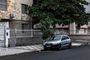 Rua urbana tranquila com prédios residenciais e um carro estacionado.