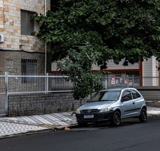 Rua urbana tranquila com prédios residenciais e um carro estacionado.