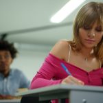 Dois estudantes concentram-se em uma atividade de escrita em uma sala de aula.