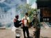 Três agentes realizam fumigação em uma rua residencial para combater mosquitos.