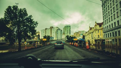 Obras viárias em andamento em uma rua cercada por prédios e estruturas urbanas.