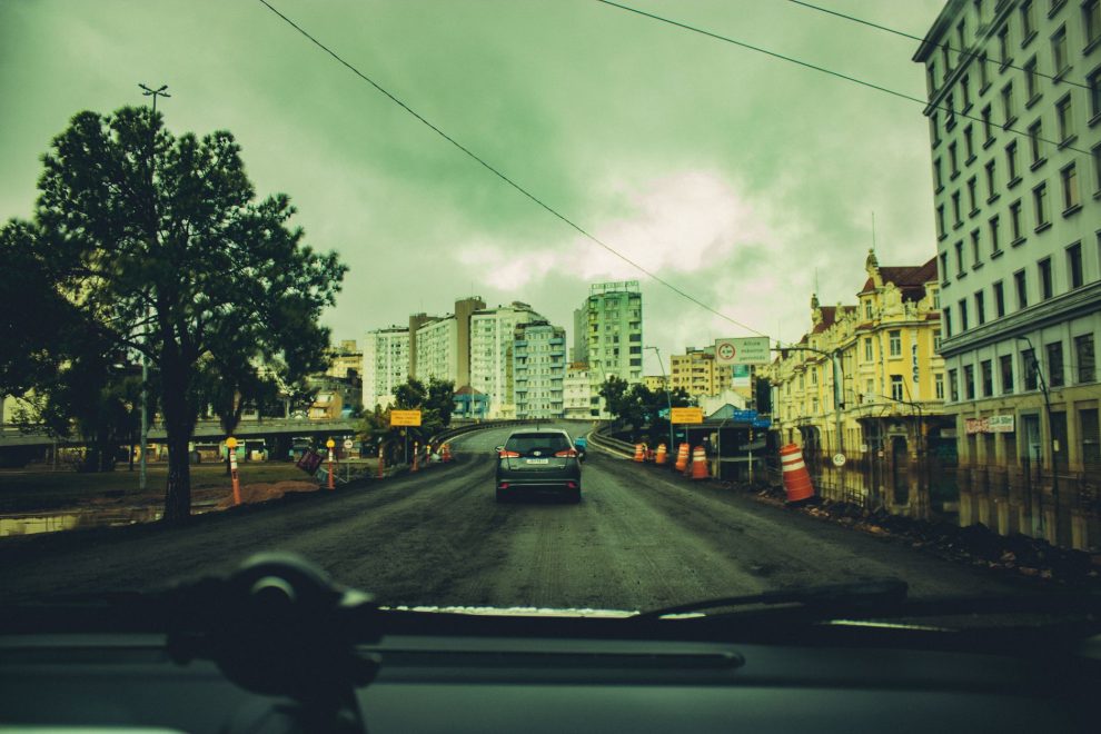 Obras viárias em andamento em uma rua cercada por prédios e estruturas urbanas.
