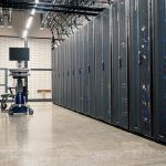 Racks metálicos com servidores, equipamentos de rede e cabos em um datacenter moderno.