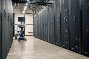Racks metálicos com servidores, equipamentos de rede e cabos em um datacenter moderno.