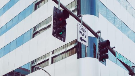 Semáforos instalados em uma via urbana, diante de edifícios