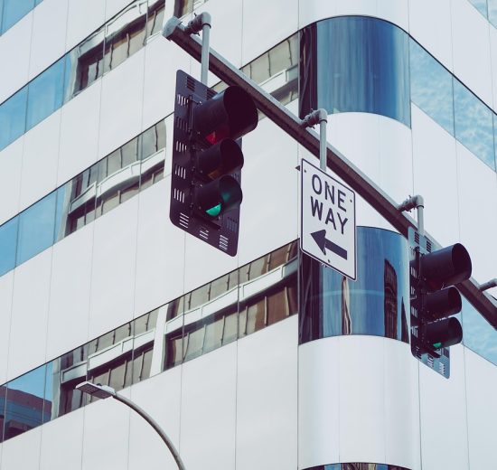 Semáforos instalados em uma via urbana, diante de edifícios