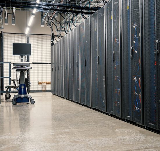Racks metálicos com servidores, equipamentos de rede e cabos em um datacenter moderno.