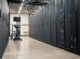 Racks metálicos com servidores, equipamentos de rede e cabos em um datacenter moderno.